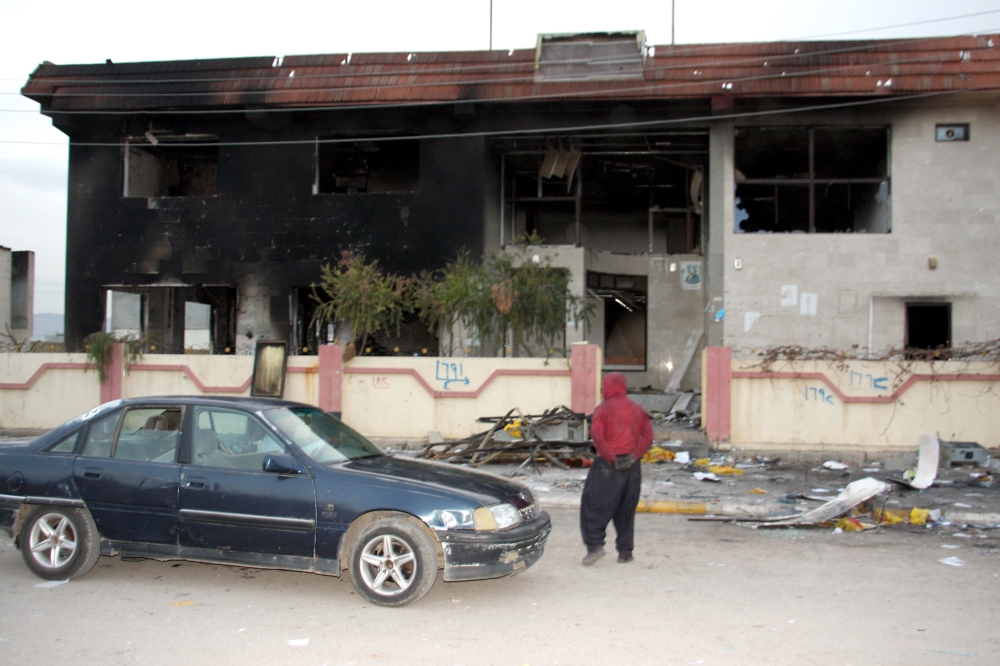 A man stands in front of the offices of a Kurdish political party after in was set ablaze by protestors in Piramagroon, west of Sulaimaniyah, in the Kurdish autonomous region of northern Iraq. — AFP