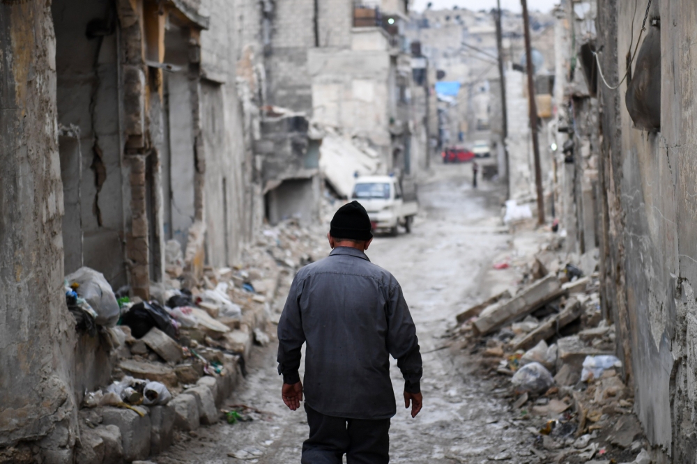 Syrian Khayro Moselmani walks amidst debris in the former rebel-held Kalasse neighborhood in the northern Syrian city of Aleppo. — AFP