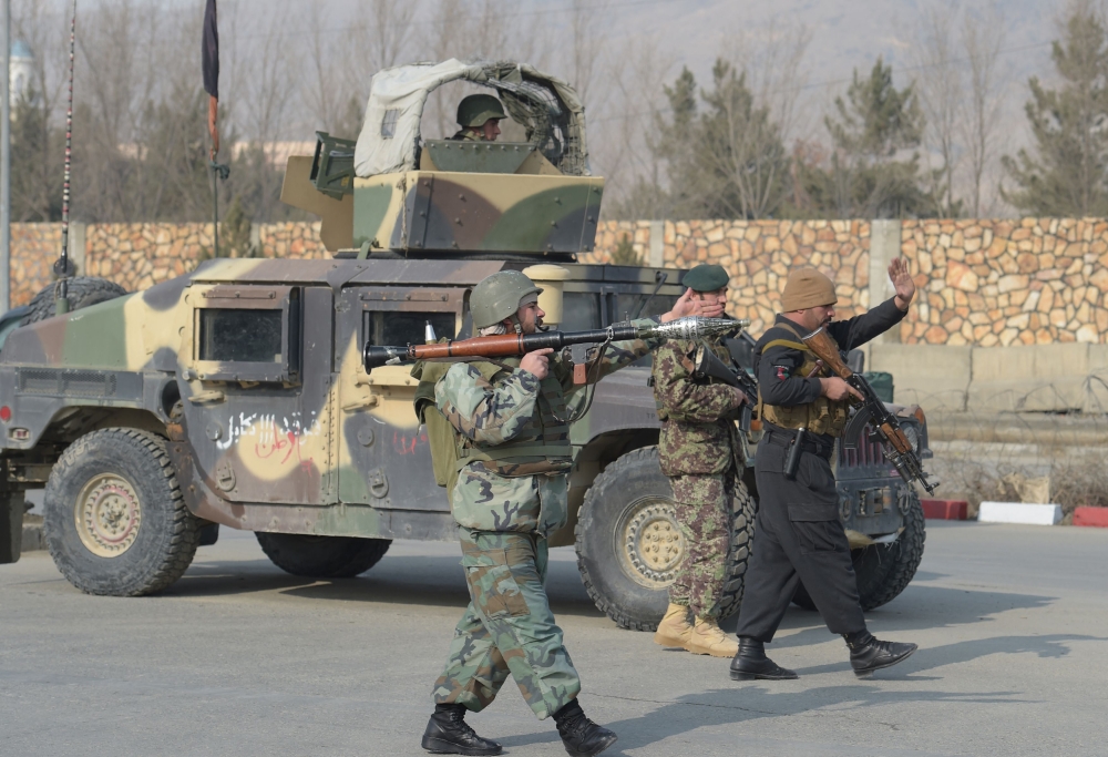 Afghan security forces stand guard at the side of an ongoing attack in Kabul on Monday. — AFP