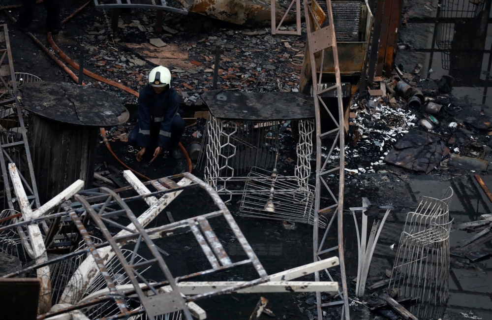 A firefighter rests amidst debris at a restaurant destroyed in a fire in Mumbai, India, on Friday. — Reuters