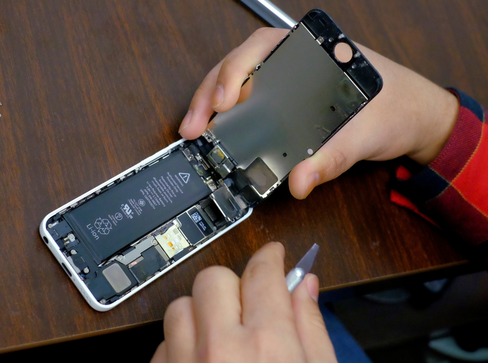 A battery is exposed as a man tries to repair an iPhone in a repair store in New York in this Feb. 17, 2016 file photo. — Reuters