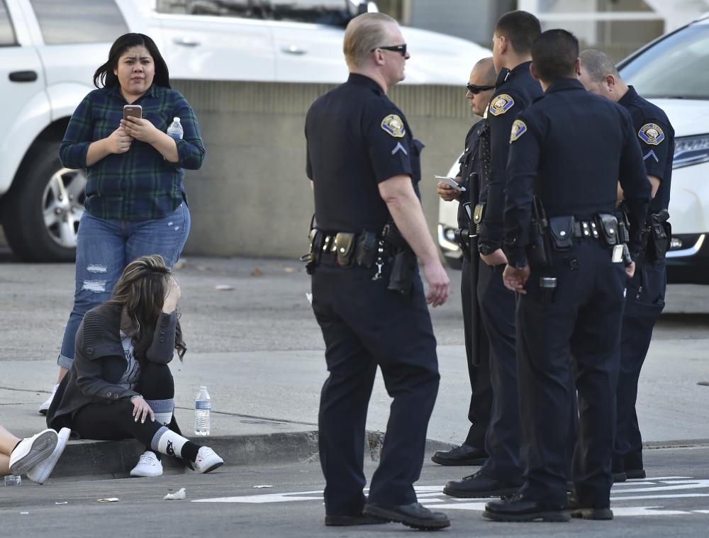 Employees from a nearby business sit with police after the Long Beach police responded to an active shooter in Long Beach, California, Friday. - AP
