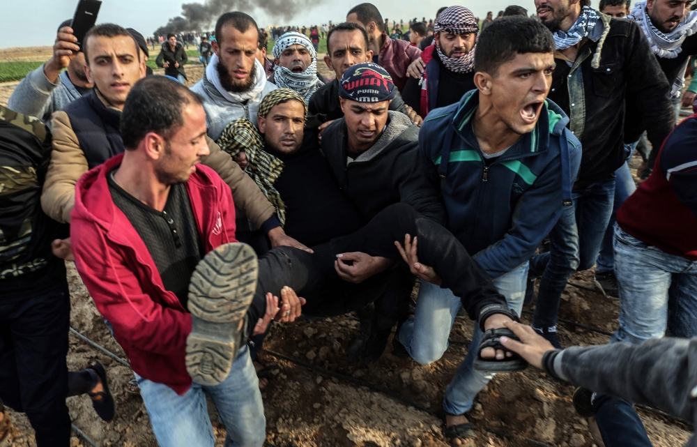 Palestinians carry a wounded protesters near the Israel-Gaza border east of the southern Gaza strip city of Khan Yunis. — AFP