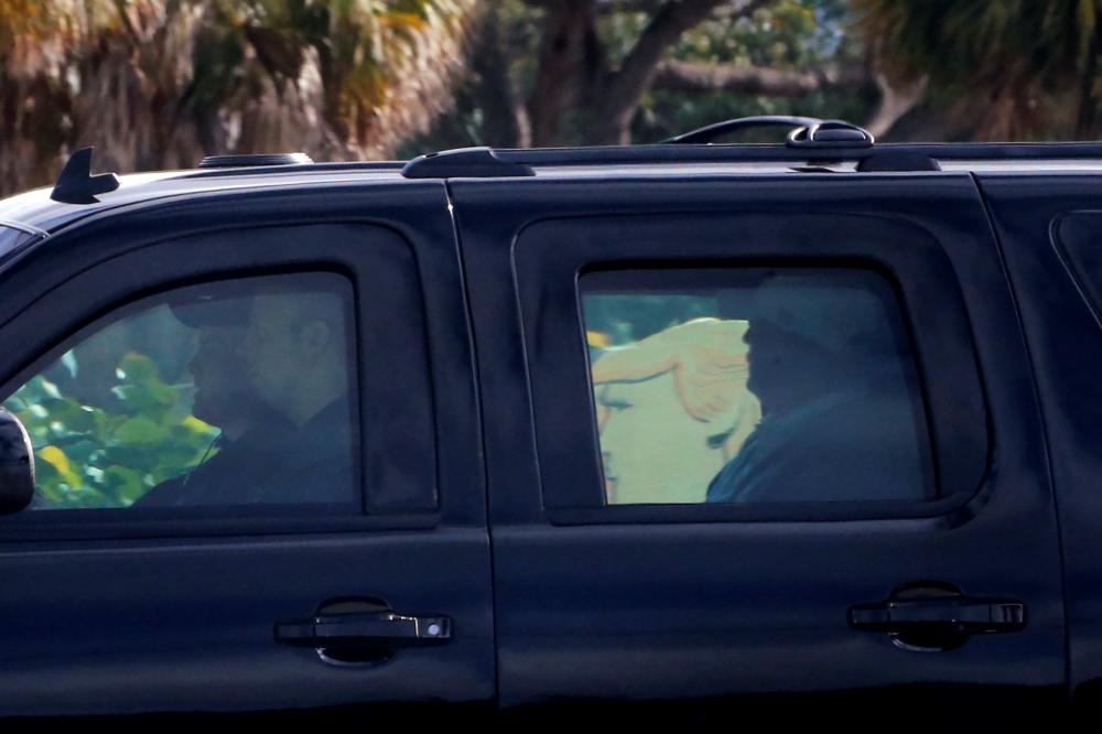 US President Donald Trump, from the window of his car, passes a protester with a sign in his image, as he departs after spending several hours at his Trump International Golf Club in West Palm Beach, Florida, on Saturday. — Reuters