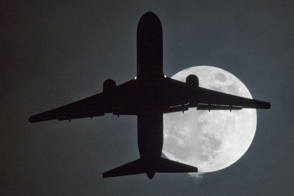 A plane flys in front of a “super moon” on its approach to London Heathrow Airport on Monday. — AFP