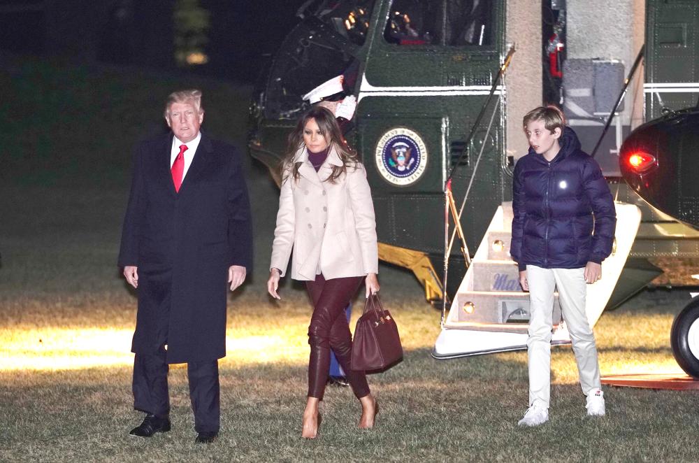 US President Donald Trump, Melania Trump and son Barron walk across the South Lawn upon return to the White House in Washington on Monday after vacationing at the Mar-a-Lago estate in Florida. — AFP