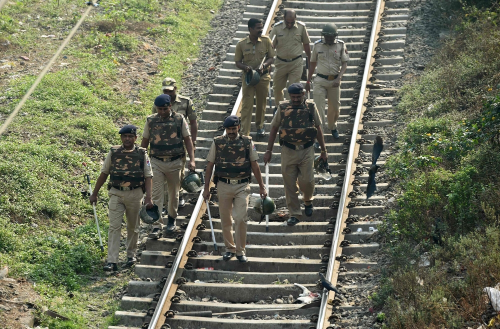 Indian policemen walk along railway tracks during Republican Party of India (RPI) supporters protest in Mumbai on Wednesday. — AFP