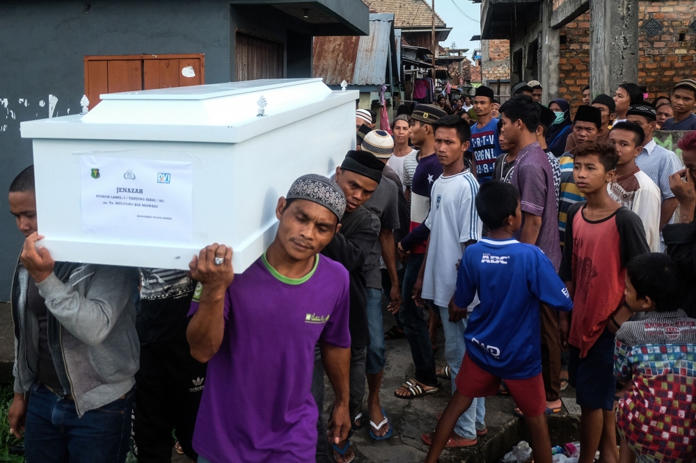 Relatives carry the coffin of a victim of a boat accident in Palembang, South Sumatra province on Friday, after a boat carrying 55 people hit a large wave and sank amid bad weather. — AFP
