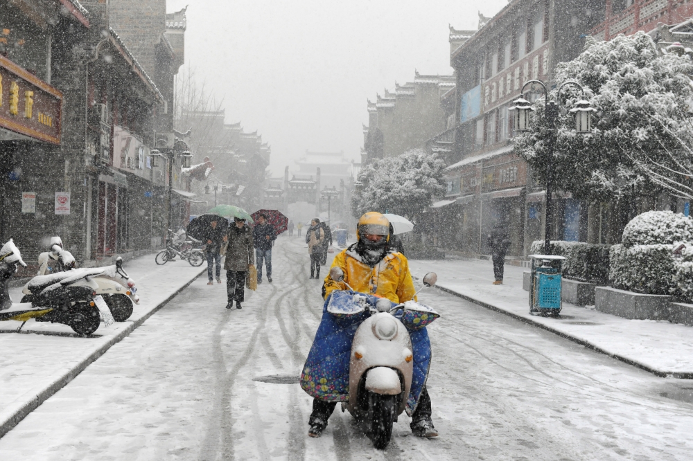 People are seen amid snow in Xiangyang, Hubei province, China, in this Jan. 3, 2018 file photo. — Reuters