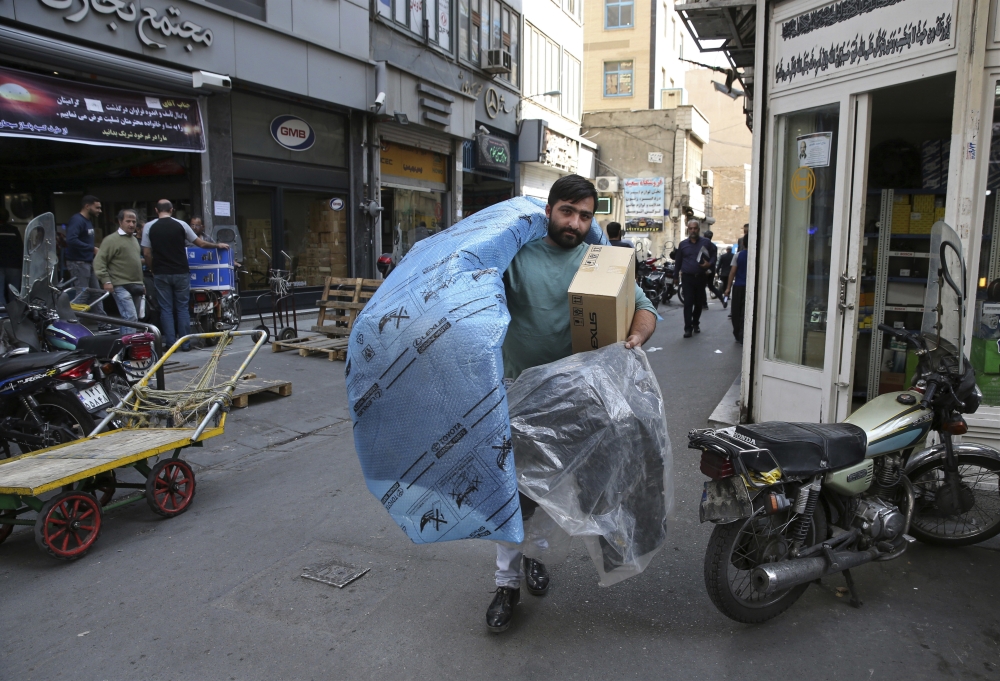 A man carries car parts at a market in downtown Tehran.  — AP