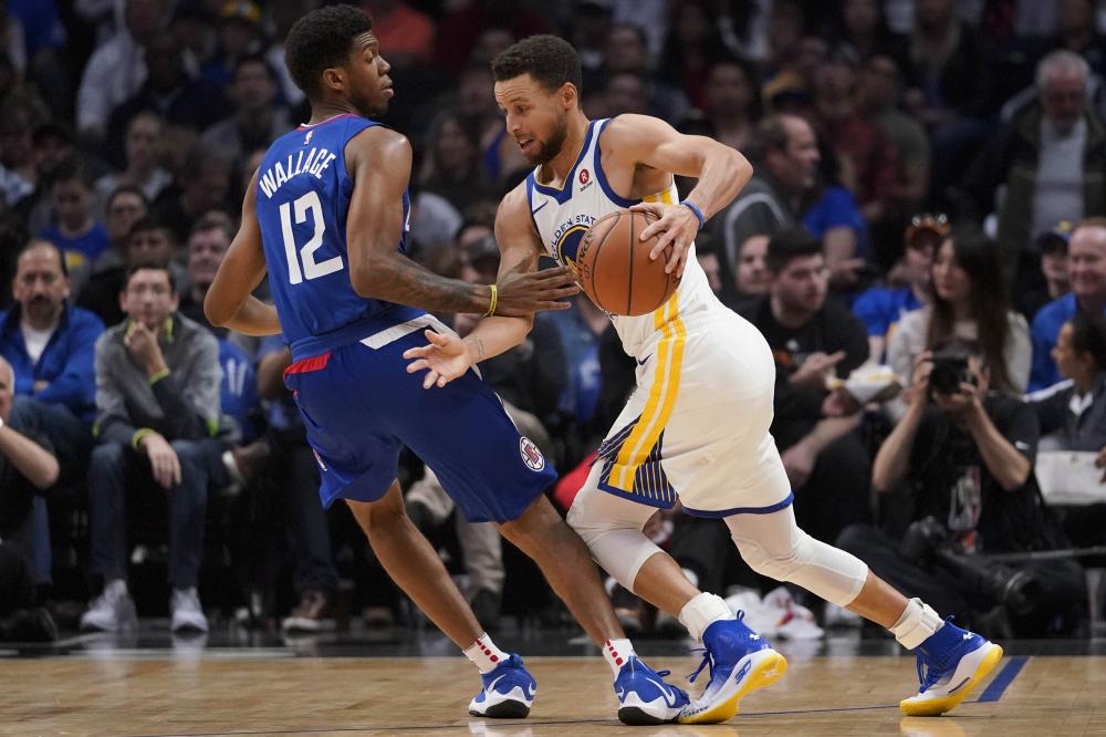 Golden State Warriors’ guard Stephen Curry (R) tries to drive past Los Angeles Clippers’ guard Tyrone Wallace during their NBA game at Staples Center in Los Angeles Saturday. — Reuters