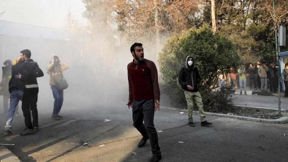 University students attend a protest inside Tehran University while a smoke grenade is thrown by anti-riot Iranian police. — AP