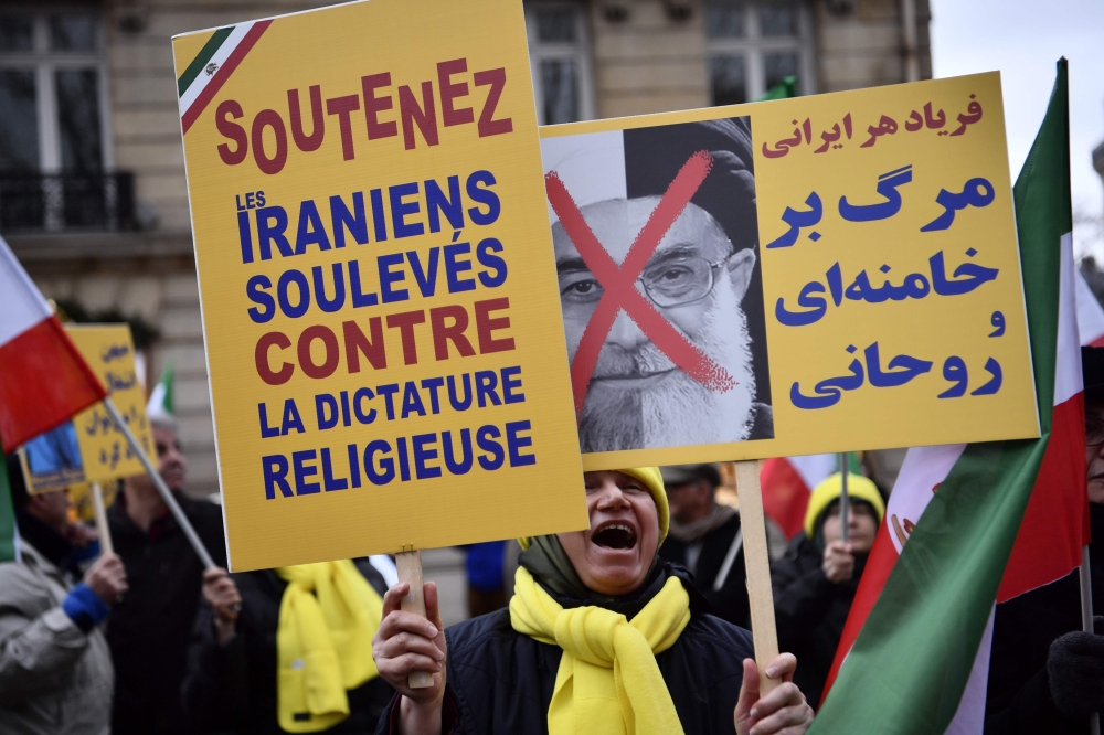 Protesters in Paris hold placards reading 