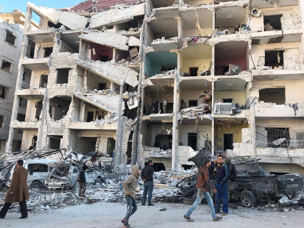 People look at the damage in the aftermath of an explosion in a rebel-held area of the northwestern Syrian city of Idlib on Monday. — AFP