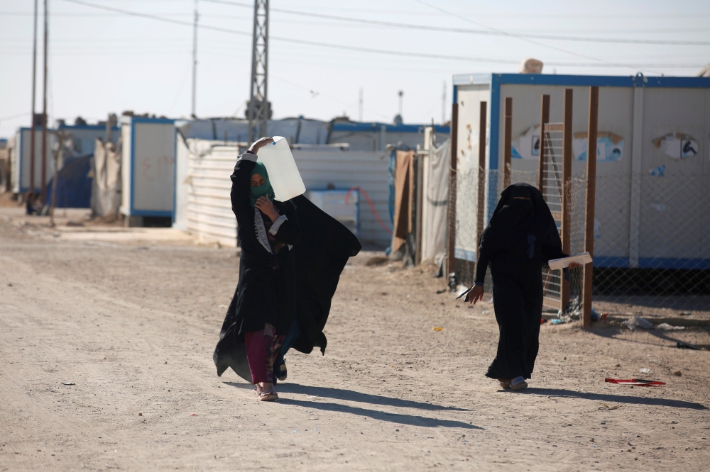 A displaced Iraqi woman carries a water container at the Amriyat Al-Falluja camp in Anbar province, Iraq. — Reuters