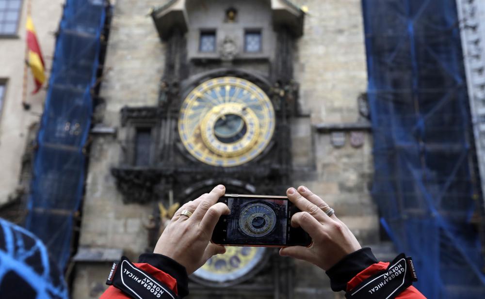 A woman takes a photo of the famed astronomical clock at the Old Town Square in Prague, Czech Republic, on Monday. — AP