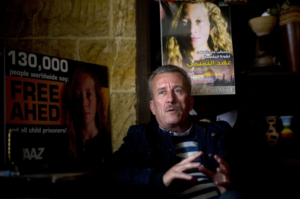 Palestinian Bassem Tamimi speaks in front of a poster showing his daughter Ahed at his home in Nabi Saleh near the West Bank city of Ramallah. — AP