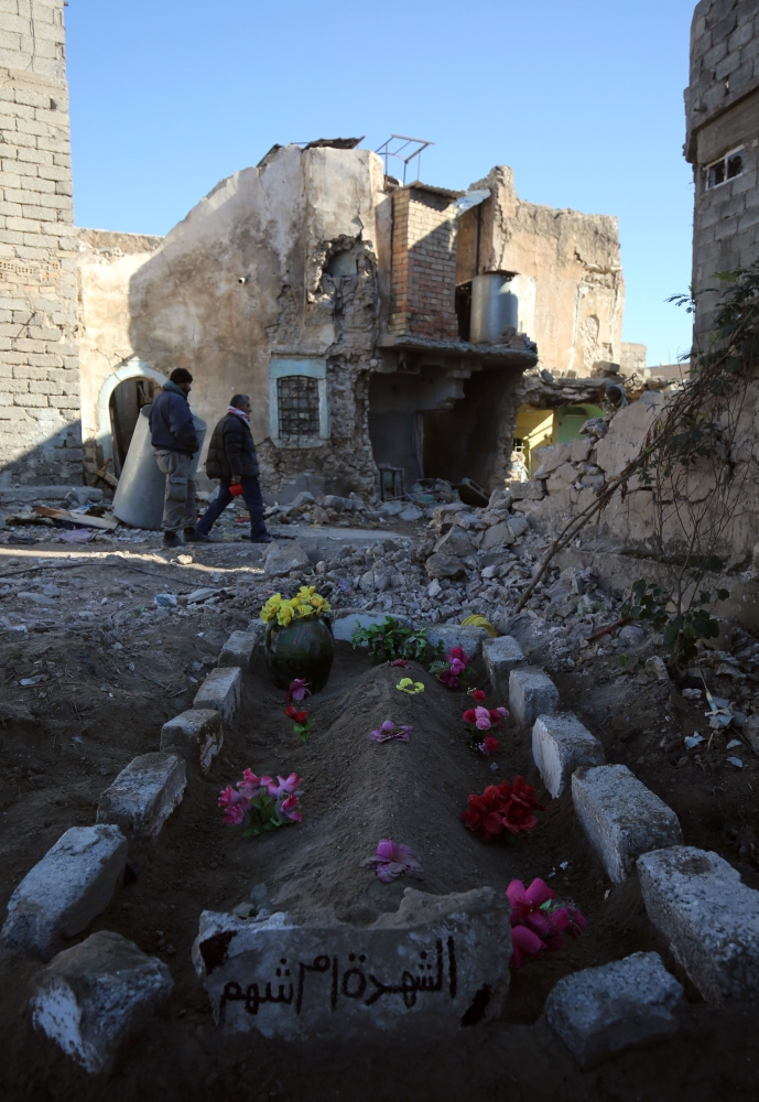 An Iraqi man stands near wrecked vehicles in a debris-strewn alleyway in Mosul's Old City.