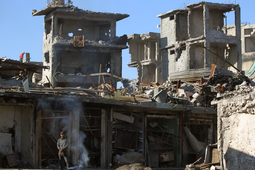 An Iraqi man stands near wrecked vehicles in a debris-strewn alleyway in Mosul's Old City.