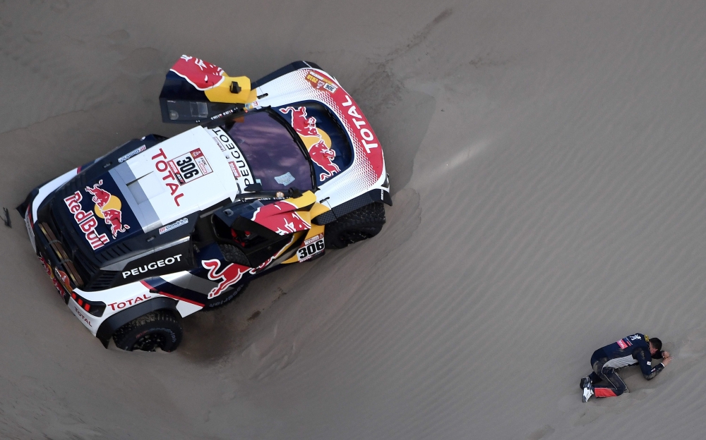 The co-driver of Peugeot's French driver Sebastien Loeb, Daniel Elena (R), from Monaco, gestures on the ground after they ran into sand trouble and he suffered an injury, during the 2018 Dakar Rally Stage 5 between San Juan De Marcona and Arequipa in Peru, on Wednesday.  — AFP