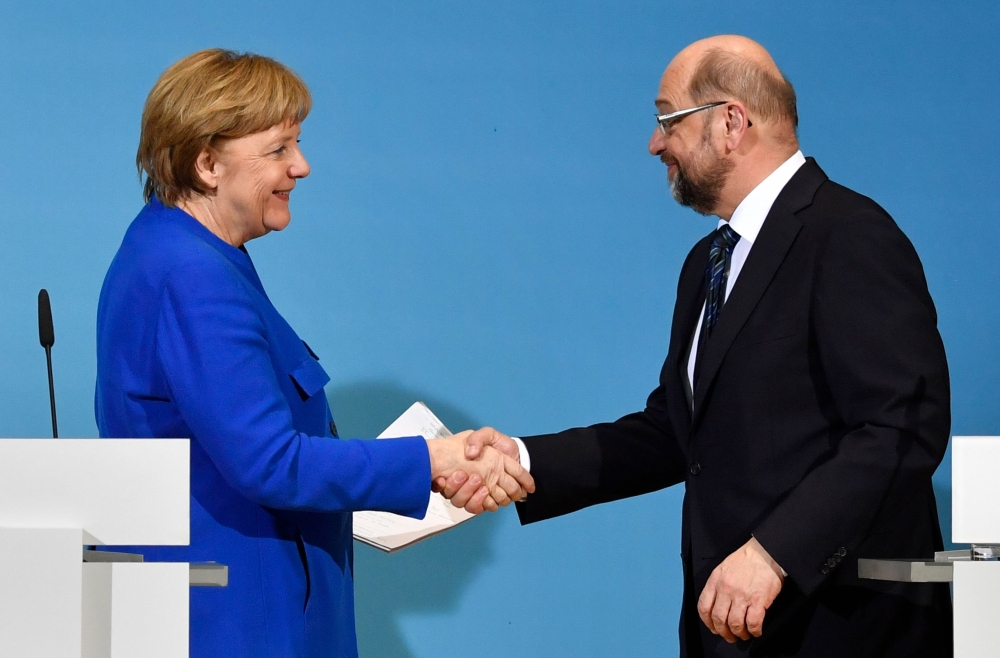German Chancellor Angela Merkel (CDU) shakes hands with the leader of the Social Democratic Party (SPD) Martin Schulz (R) at the end of a joint press conference with the leader of the Christian Social Union (CSU), after talks to form a new government on Friday at the SPD headquarters in Berlin. — AFP