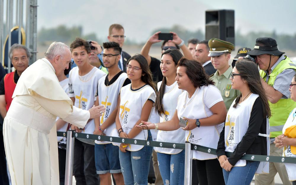 Pope Francis greets youths upon his arrival at the international airport in Santiago, Chile, Monday. — AP