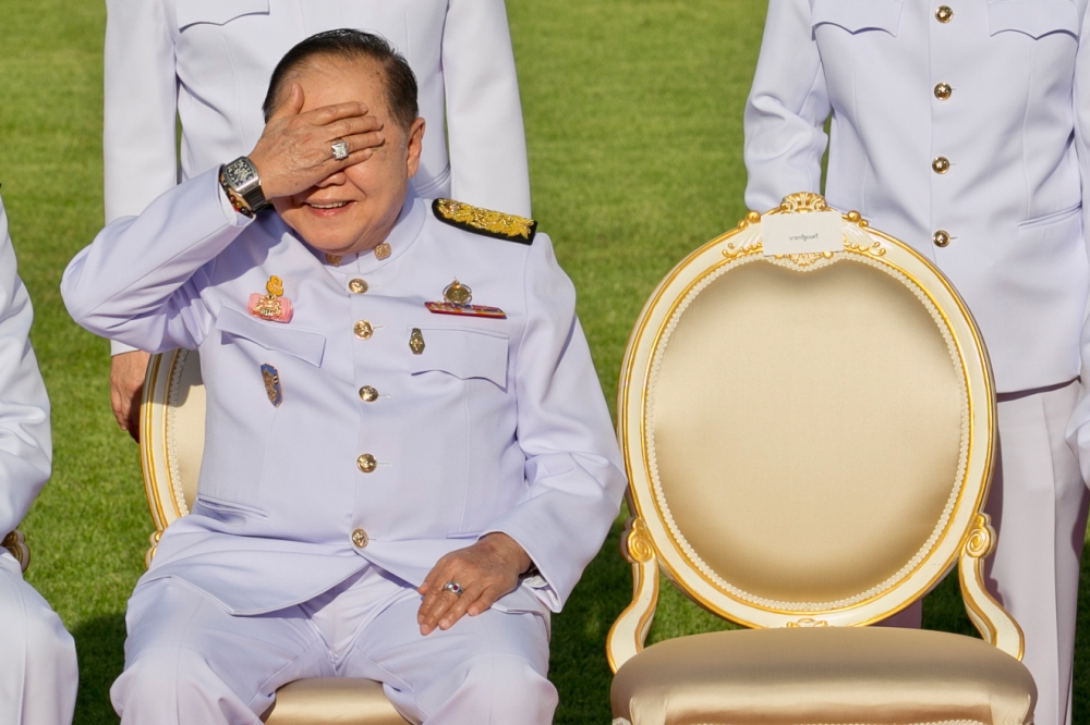 In this photograph taken last month, Thailand's junta number two Prawit Wongsuwan covers his eyes, displaying a watch he is wearing, during a photo call with other members of a new cabinet in Bangkok. — AFP