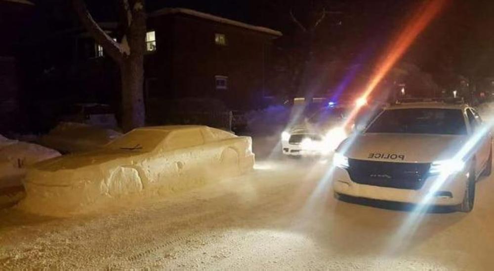 A police car is seen next to a fake car made of snow in Montreal, Canada.