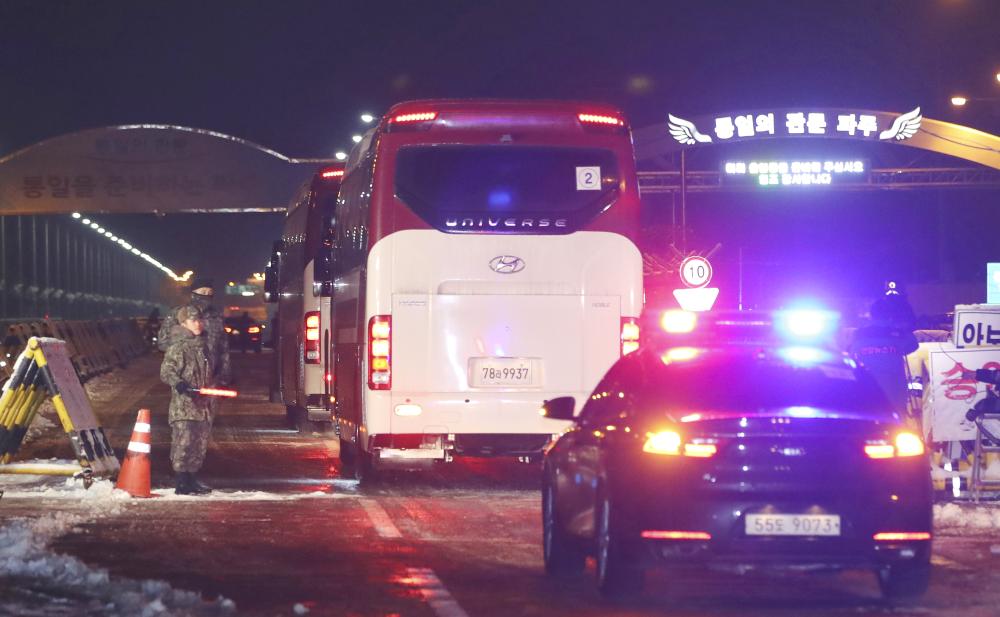 A bus carrying North Korean Hyon Song Wol, the leader of Pyongyang's all-female Moranbong Band, passes at Unification Bridge, which leads to the Panmunjom in the Demilitarized Zone, as South Korean soldiers stand by in Paju, South Korea, Monday. — AP