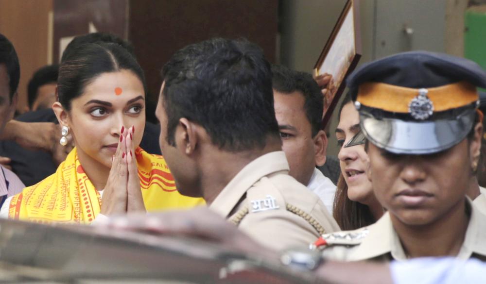 Bollywood actor Deepika Padukone, left, greets media as she leaves after offering prayers at a Hindu temple ahead of the release of her upcoming film 