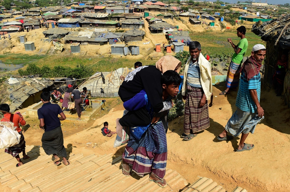 A Rohingya Muslim refugee carries his mother, who is unwell, at Kutupalong refugee camp in Bangladesh's Ukhia district, Tuesday. — AFP