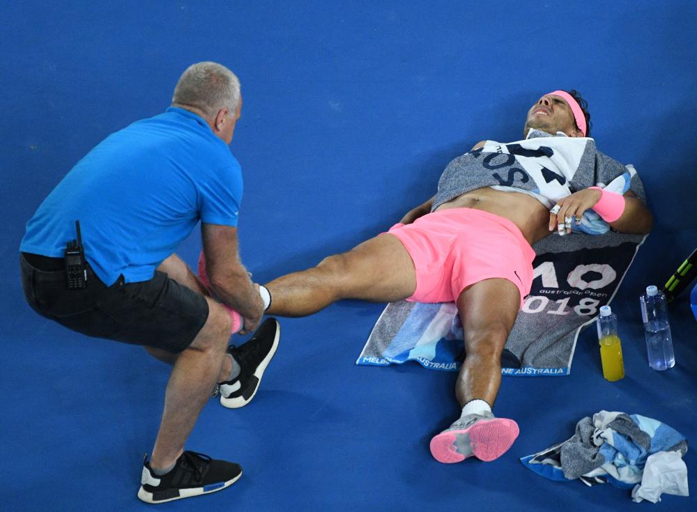 Spain’s Rafael Nadal (R) is given medical attention during his match against Croatia’s Marin Cilic at the Australian Open Tuesday. — AFP