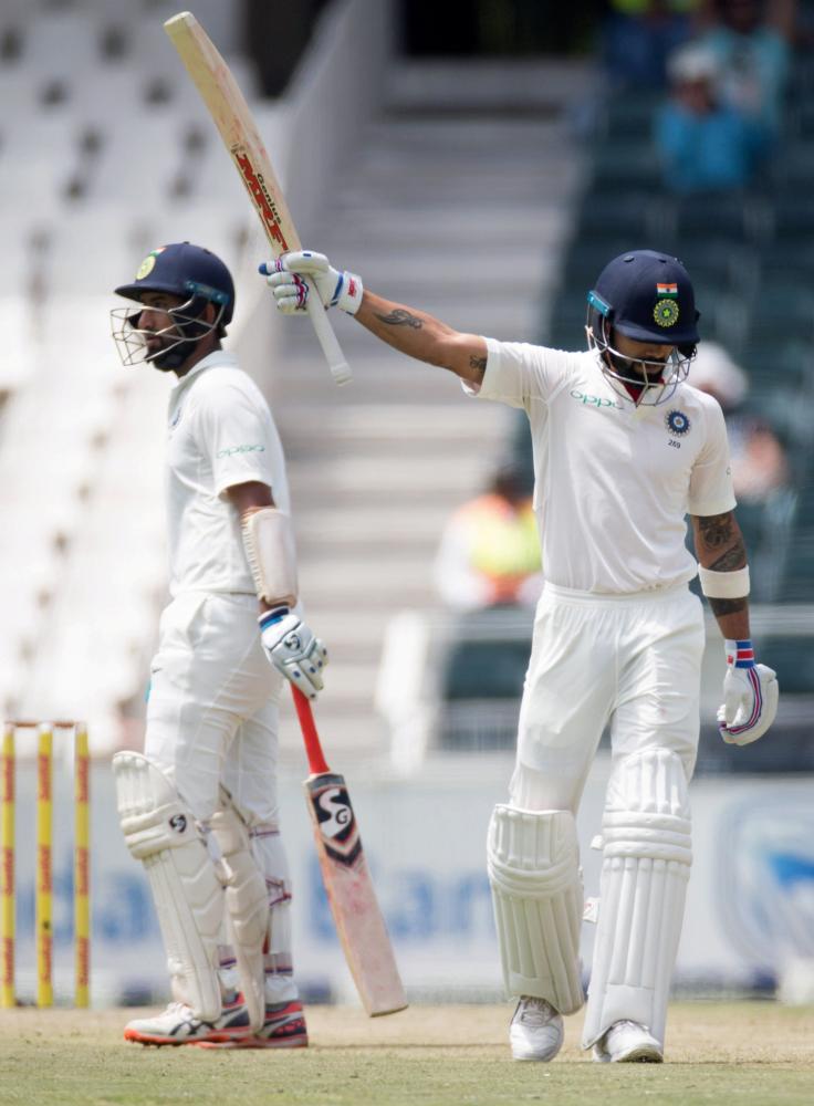 India’s skipper Virat Kohli (R) celebrates scoring 50 as teammate Cheteshwar Pujara looks on during their cricket Test match against South Africa at the Wanderers Stadium, Johannesburg, Wednesday. — Reuters 