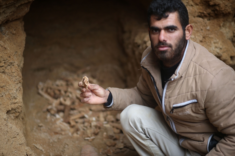 Abdul Karim Al-Kafarnah, a Palestinian resident of Beit Hanun, holds a pottery fragment at a freshly-discovered cemetery in the garden of his house in the town in the northern Gaza Strip. — AFP