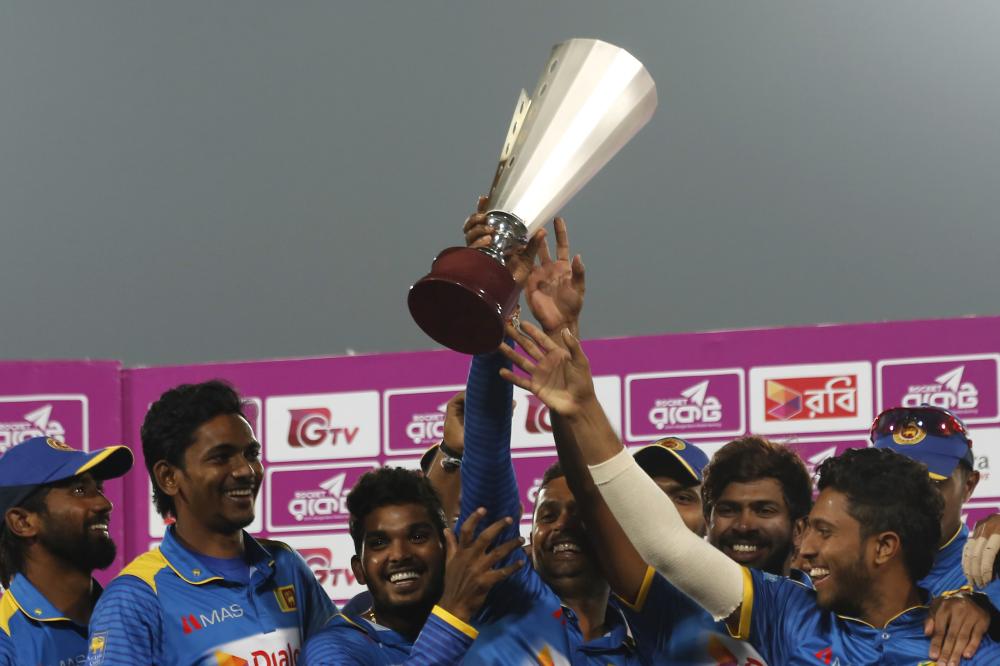 Sri Lanka's players celebrating with the trophy after winning the final of the Tri-Nation One-Day International cricket series against Bangladesh in Dhaka Saturday. — AP