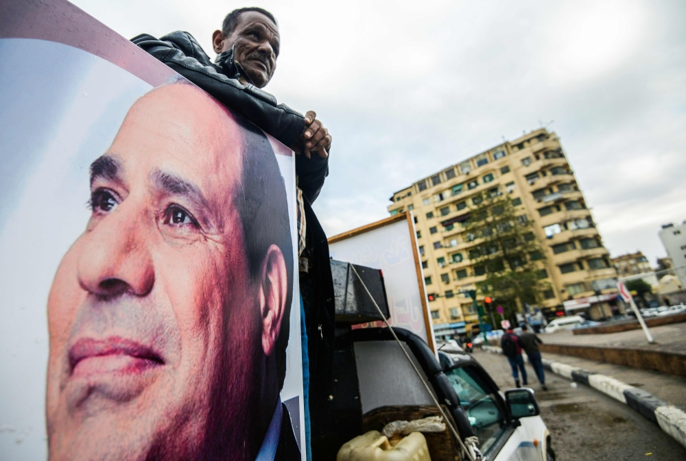 A supporter of Egyptian President Abdel Fattah El-Sisi stands in the back of a pickup truck bearing his portrait and loudspeakers, in the capital Cairo's Tahrir square. — AFP