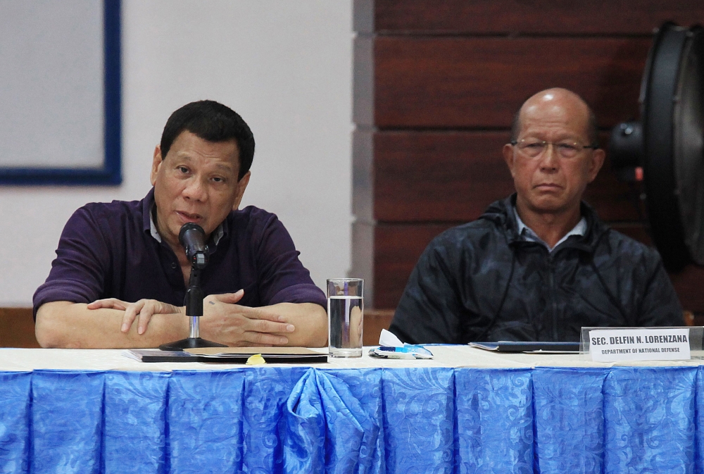 Philippine President Rodrigo Duterte, left, speaks in a meeting with local officials as Defense Secretary Delfin Lorenzana, right, look on during a visit to Legazpi City, Albay province, south of Manila, on Monday. — AFP