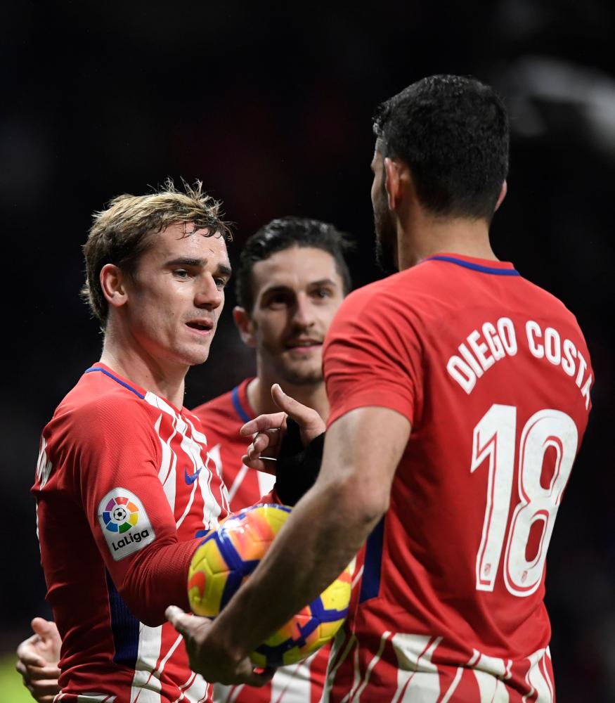 Atletico Madrid’s Antoine Griezmann (L), Koke (C) and Diego Costa celebrate their victory at the end of the Spanish league football match against Valencia at the Wanda Metropolitano Stadium in Madrid Sunday. — AFP