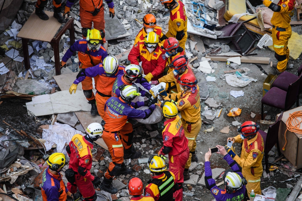 Rescue workers remove the first of two bodies of a Hong Kong Canadian couple from the Yun Tsui building, which is leaning at a precarious angle, in the Taiwanese city of Hualien on Friday. — AFP