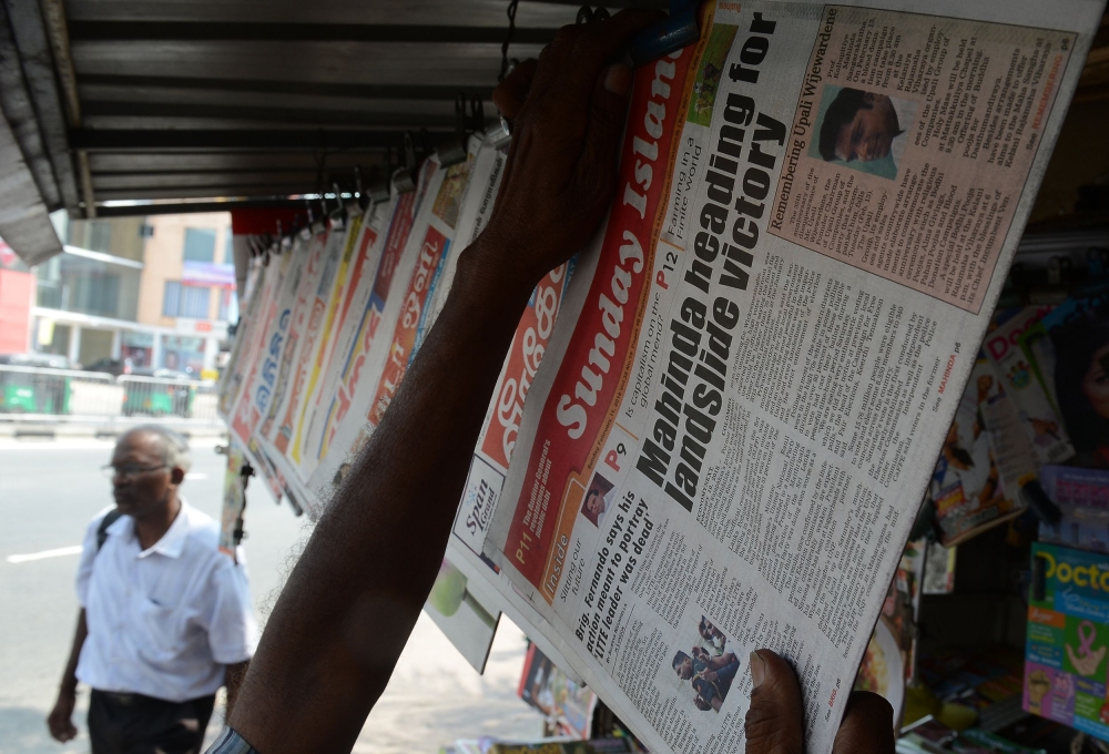 A Sri Lankan newspaper vendor sorts the Sunday papers in Colombo on Sunday. — AFP