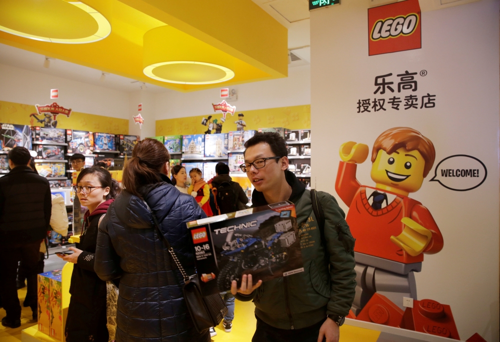 A customer carries a Lego box at a Lego store in Beijing, China. - Reuters
