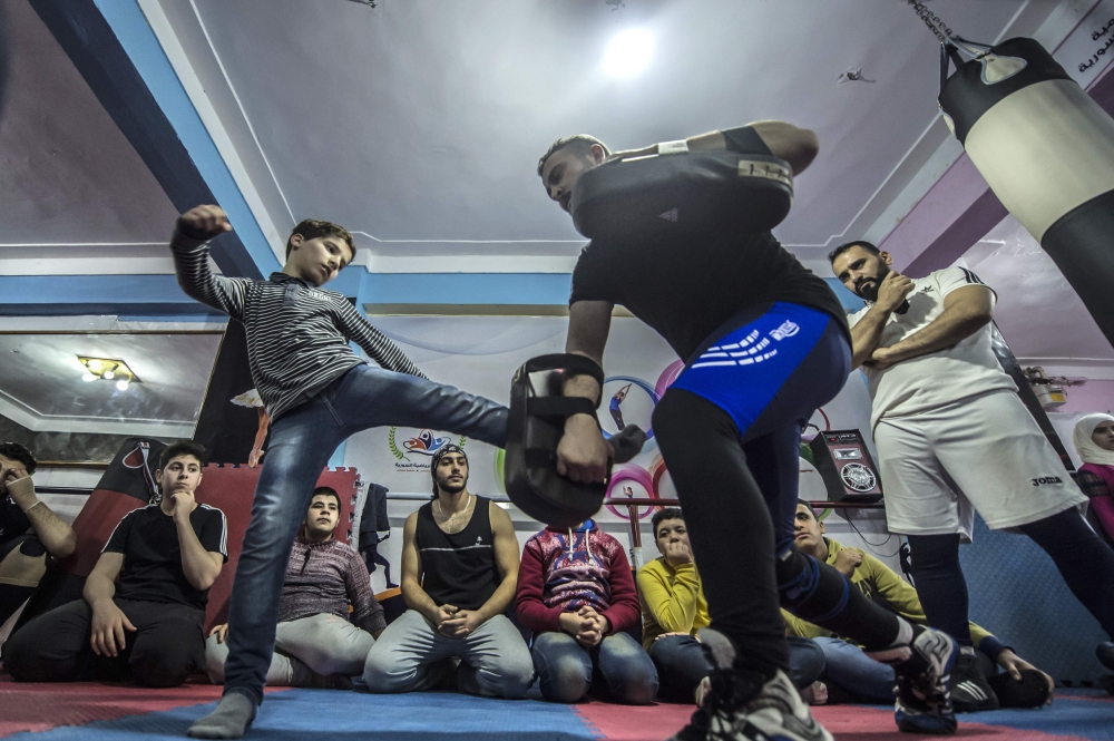 Syrian refugee Amir Al-Awad (R) watches as Adel Bazmawi (C) teaches martial arts to youth at the academy in Egypt's second city of Alexandria. — AFP