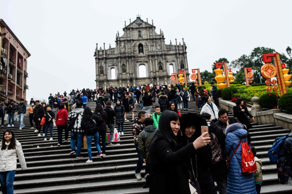 Tourists take a selfie in front of the southern stone facade of the ruins of St. Paul's Church, a 17th-century Portuguese complex in Santo Antonio in Macau. - AFP