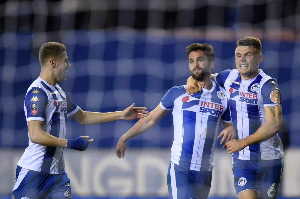 Wigan Athletic's English-born Northern Irish striker Will Grigg (C) celebrates with teammates scoring his team's first goal during the English FA Cup fifth round football match between Wigan Athletic and Manchester City at the DW Stadium in Wigan, northwest England, on Monday. — AFP