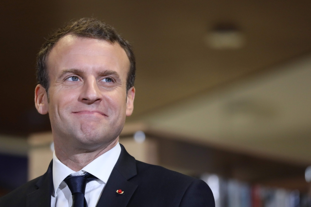 French President Emmanuel Macron smiles as he visits the mediatheque and receives the report about libraries in France, during a visit to Les Mureaux on Tuesday. — AFP 