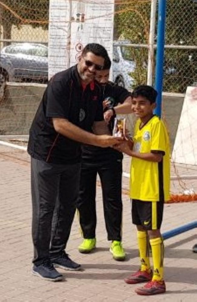 EC member Ramiz presenting the junior Top Scorer trophy to Ayaan.