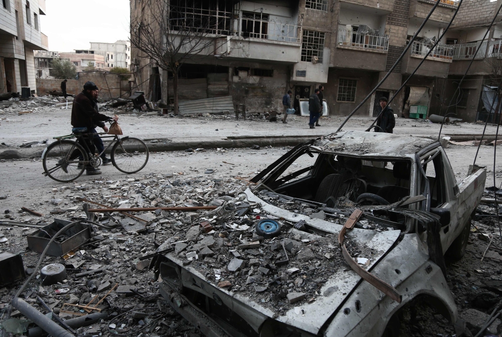 Syrians walk along a street covered in debris from shelling in Arbin in the rebel-held enclave of Eastern Ghouta. — AFP