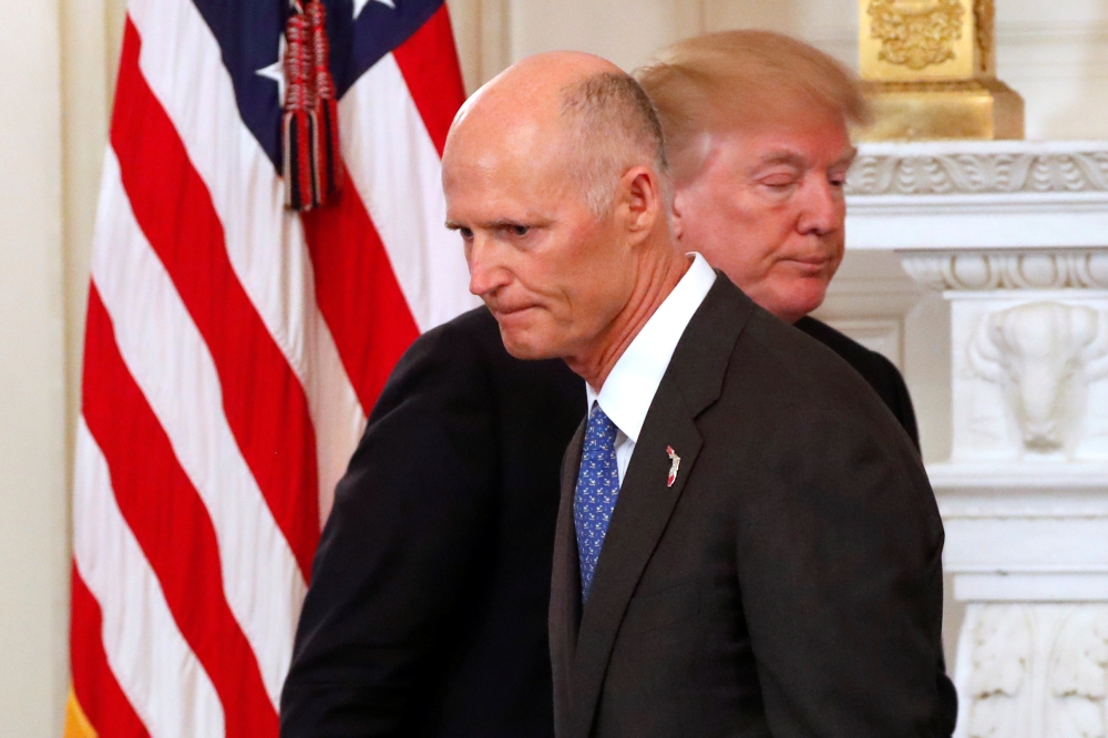 Florida Governor Rick Scott and US President Donald Trump cross paths during a discussion about school shootings with state governors from around the country at the White House in Washington on Monday. — Reuters
