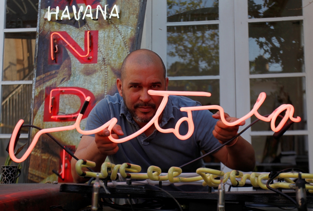 Cuban artist Kadir Lopez Nieves, who is restoring vintage neon signs of the city, poses with one reading, “Victory”, at his workshop and gallery, in Havana, Cuba in this picture. — Reuters