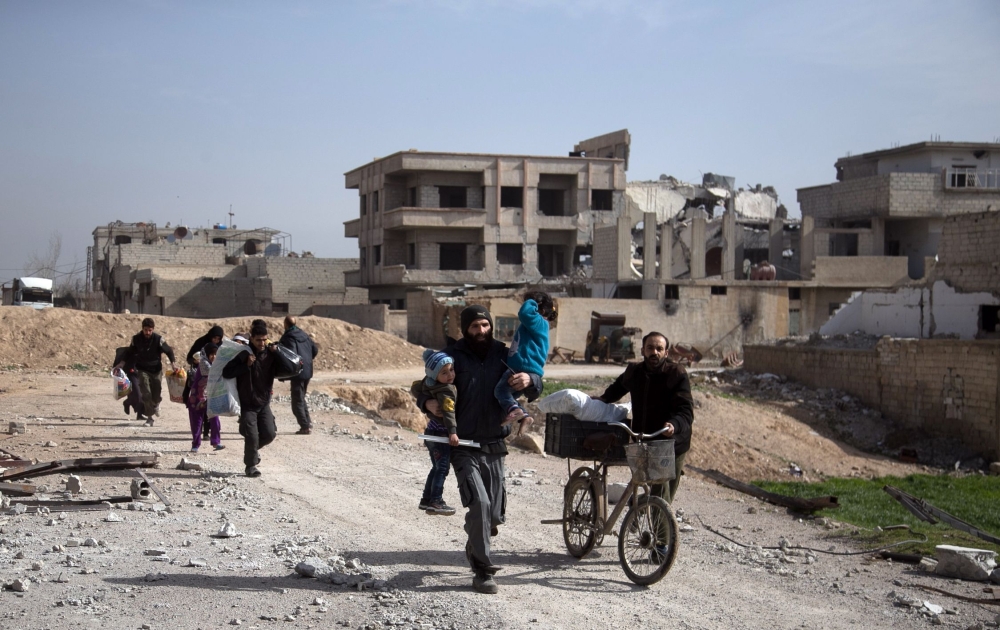 Syrians flee their homes with their belongings in the town of Beit Sawa in Syria's besieged eastern Ghouta region following air strikes.  — AFP